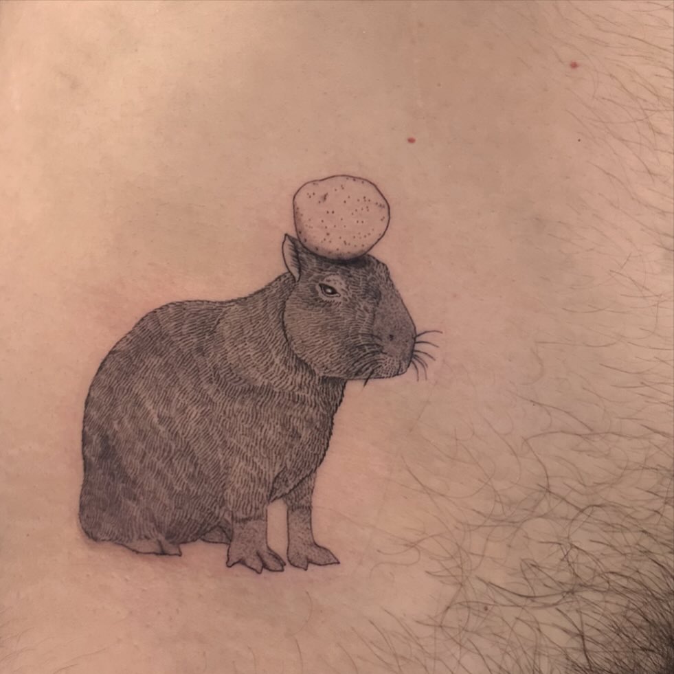 Quirky capybara tattoo with an egg on top