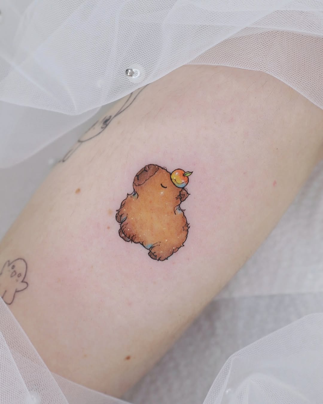 Adorable capybara tattoo enjoying a peach slice